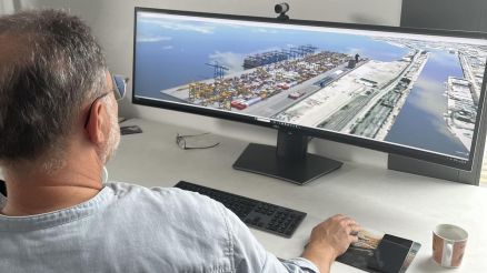 Optimizing Port Operations with CHESSCON A man sitting at a desk working with a 3D visualization of a container terminal on a wide monitor.