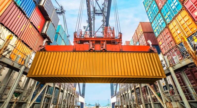 Efficient Planning with CHESSCON Terminal View Close-up of a yellow container being moved by a crane in a container terminal, surrounded by stacked containers.